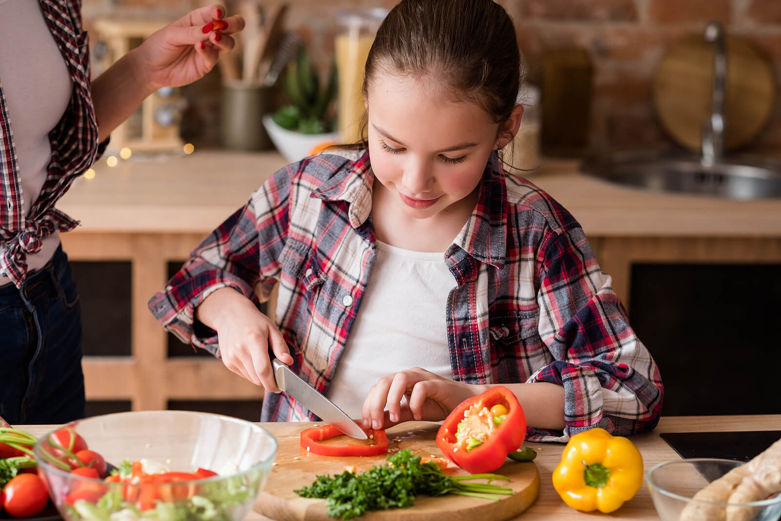 Fille aidant dans la cuisine pour augmenter la consommation de légumes.