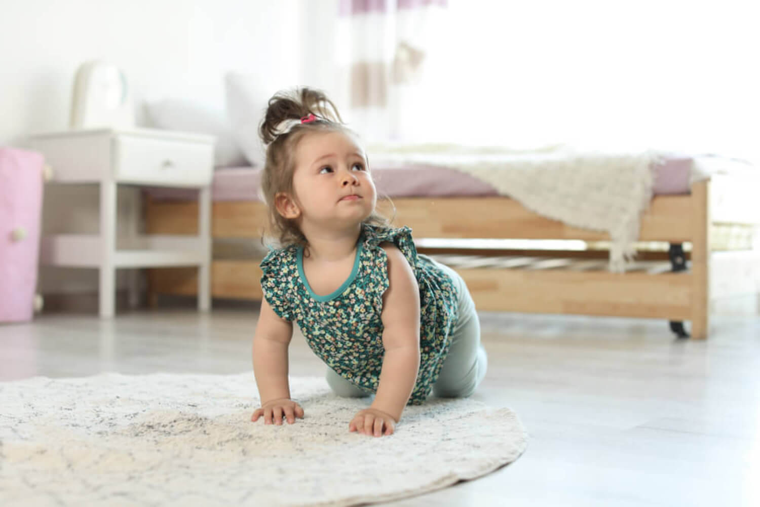 Niña aprendiendo a gatear en el suelo.