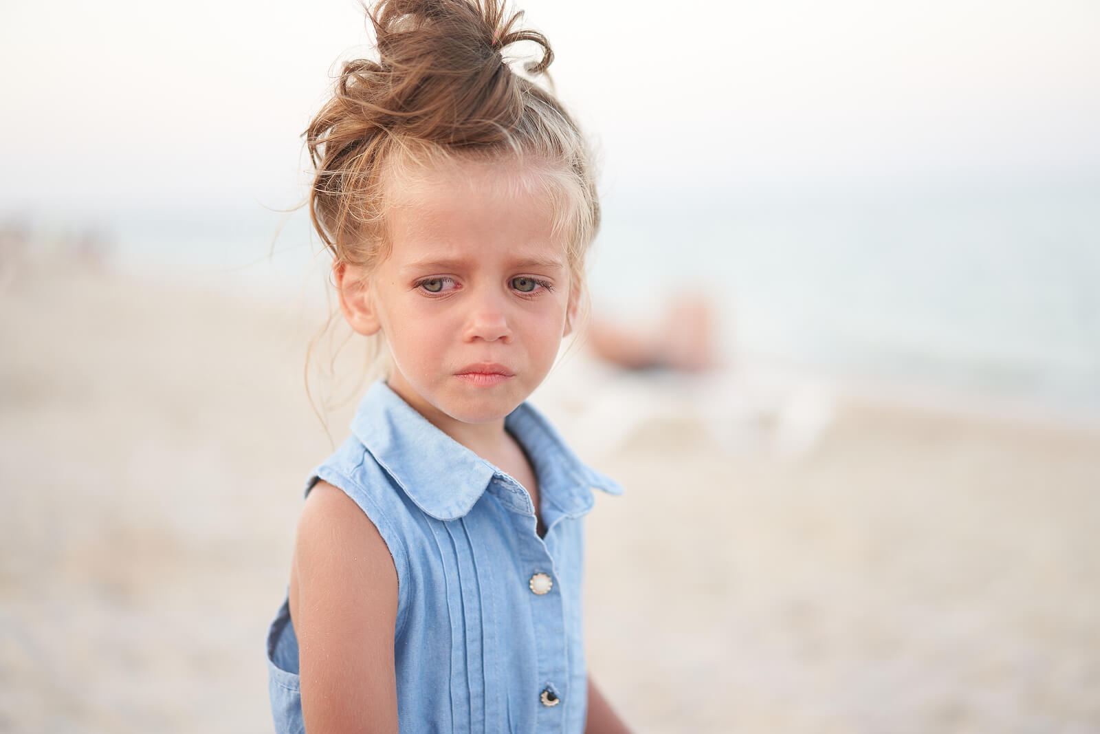 Niña llorando en la playa porque a sus padres les cuesta reconocer cuando un niño está triste.