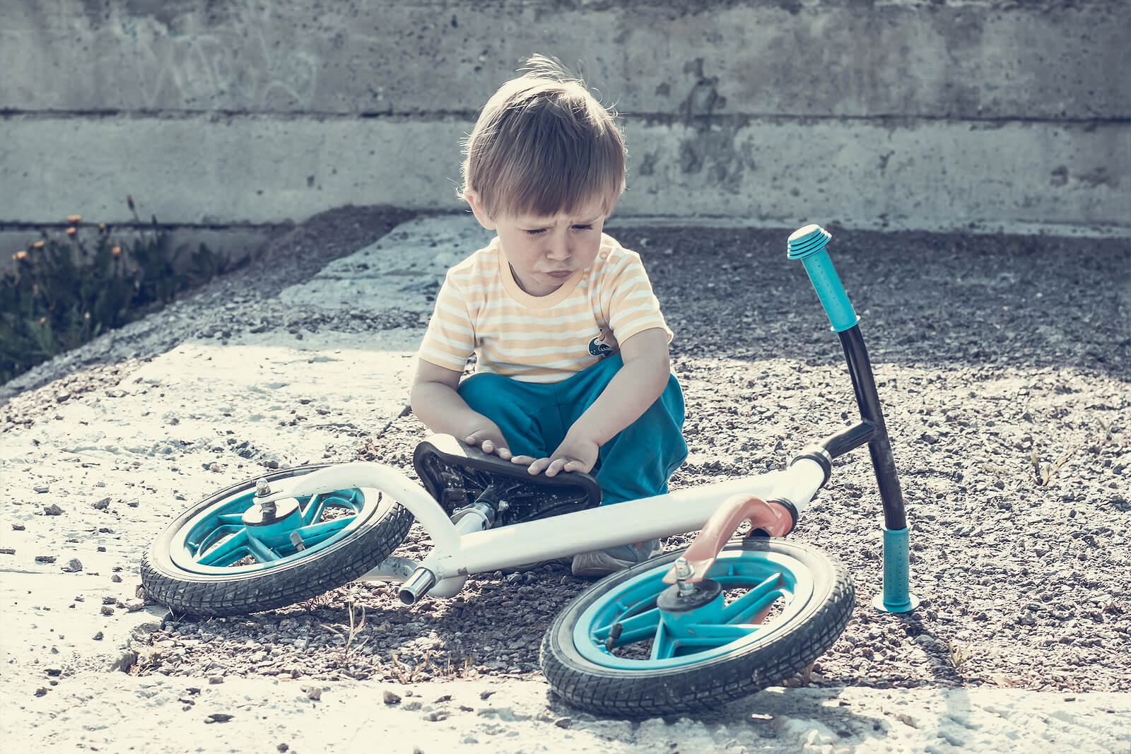 Garçon de 2 ans avec le vélo allongé sur le sol.