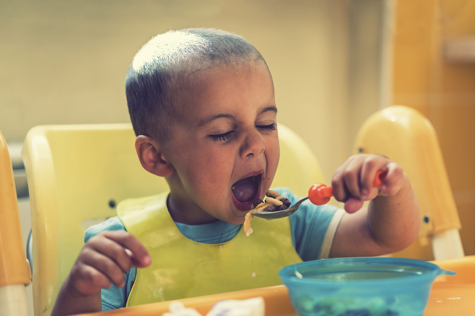 Niño de 2 años comiendo con cuchara él solo.