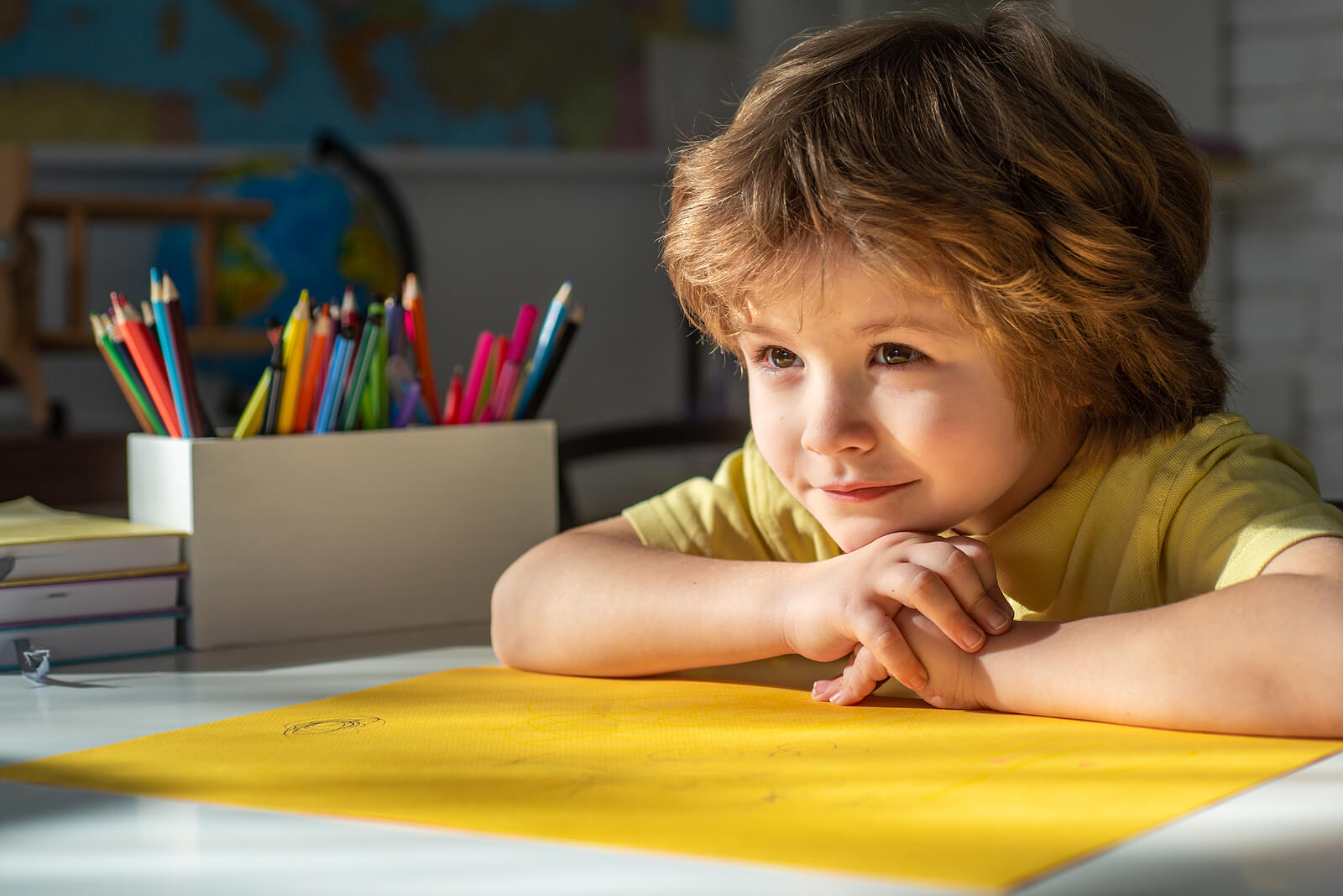 Un enfant à son bureau avec une grande feuille jaune.