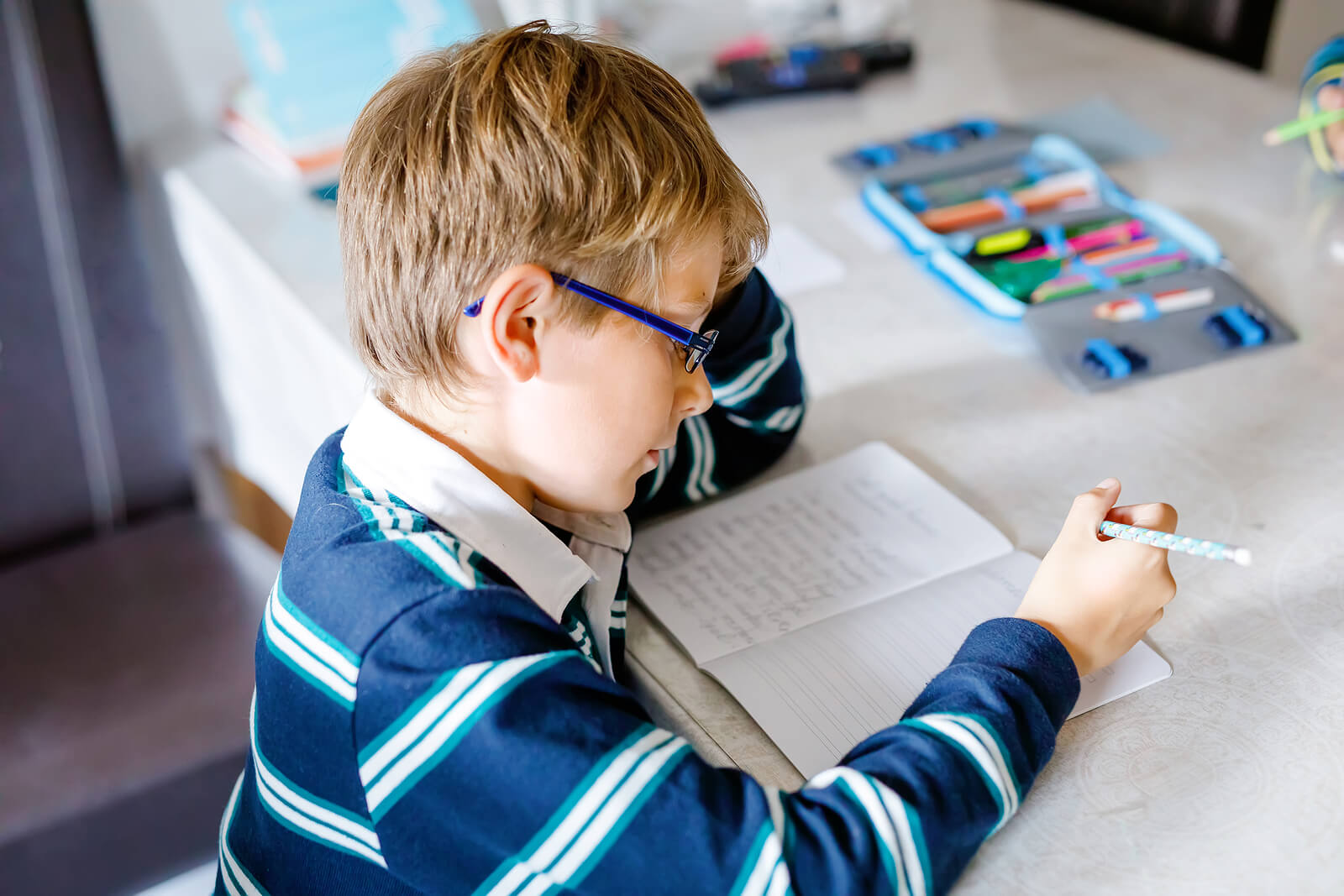 Niño escribiendo una historia para su taller de escritura creativa.