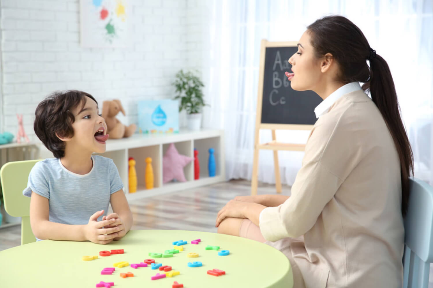 Enfant dans sa séance d'orthophonie faisant des exercices avec la langue pour corriger le rhotacisme.