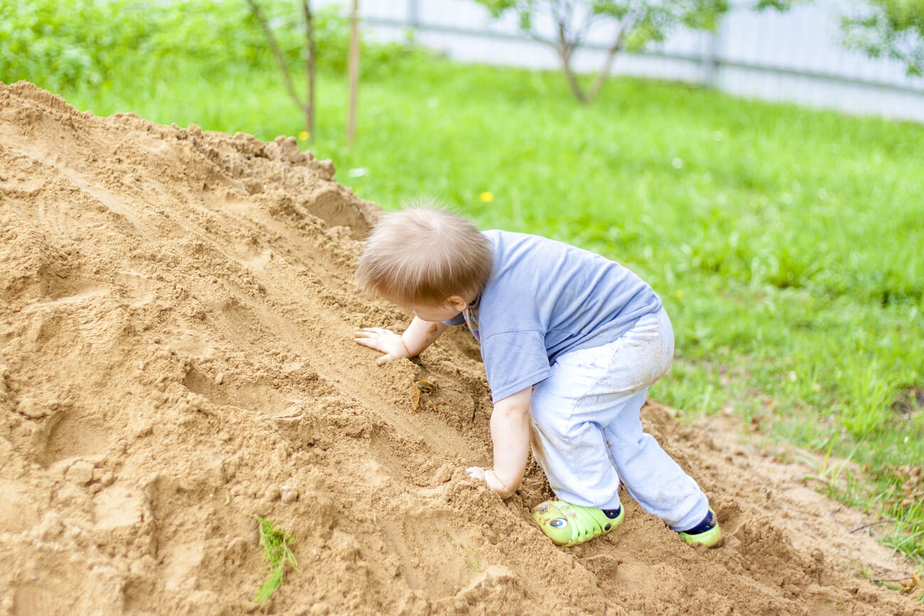 Niño subiendo un montículo de tierra para aprender a asumir riesgos.