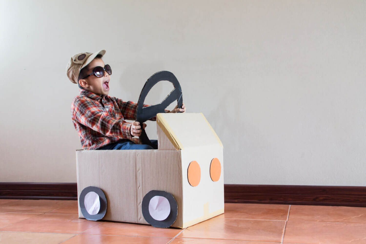 Niño jugando con un coche de cartón, una de las formas de entretener durante horas a los niños.