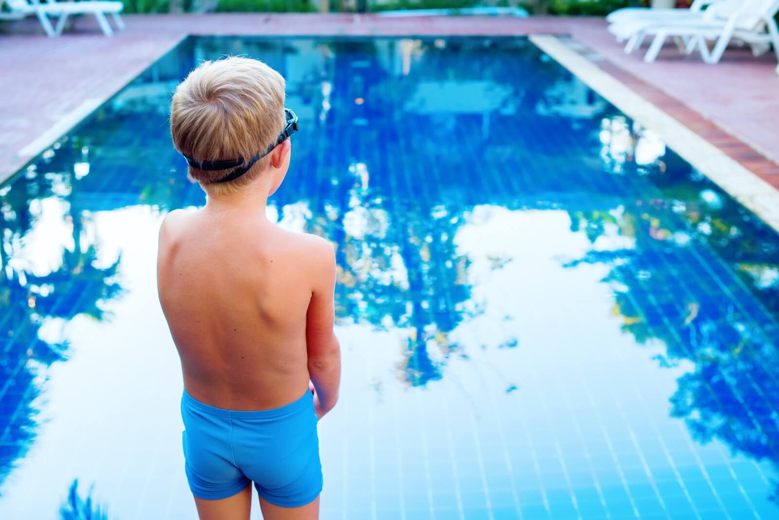 Niño mirando a la piscina porque tiene miedo al agua.