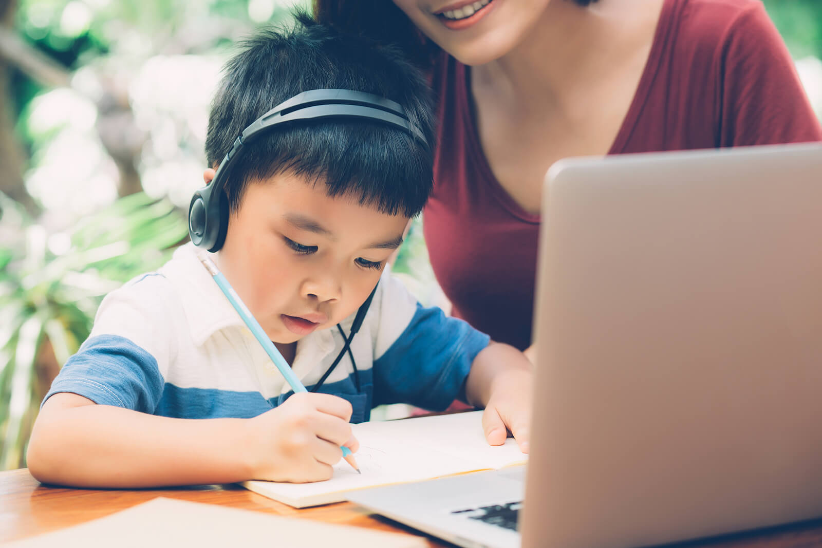 Niño con su madre participando en un taller de escritura creativa online.
