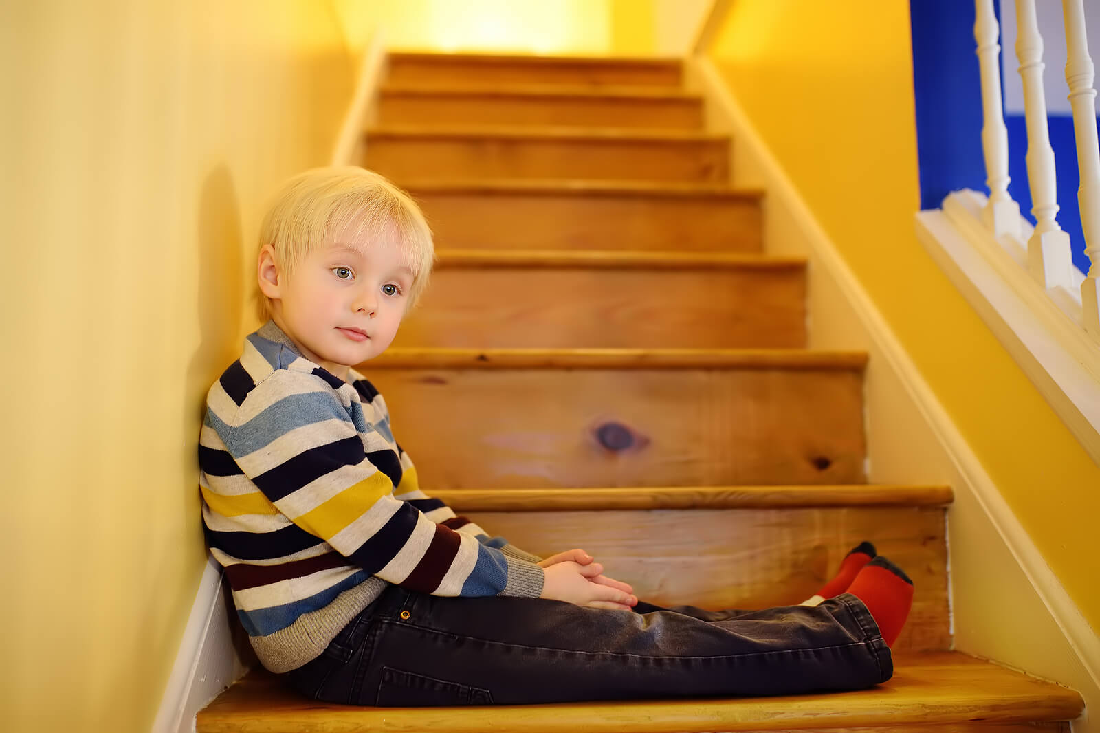 Niño obediente sentado en las escaleras de casa.