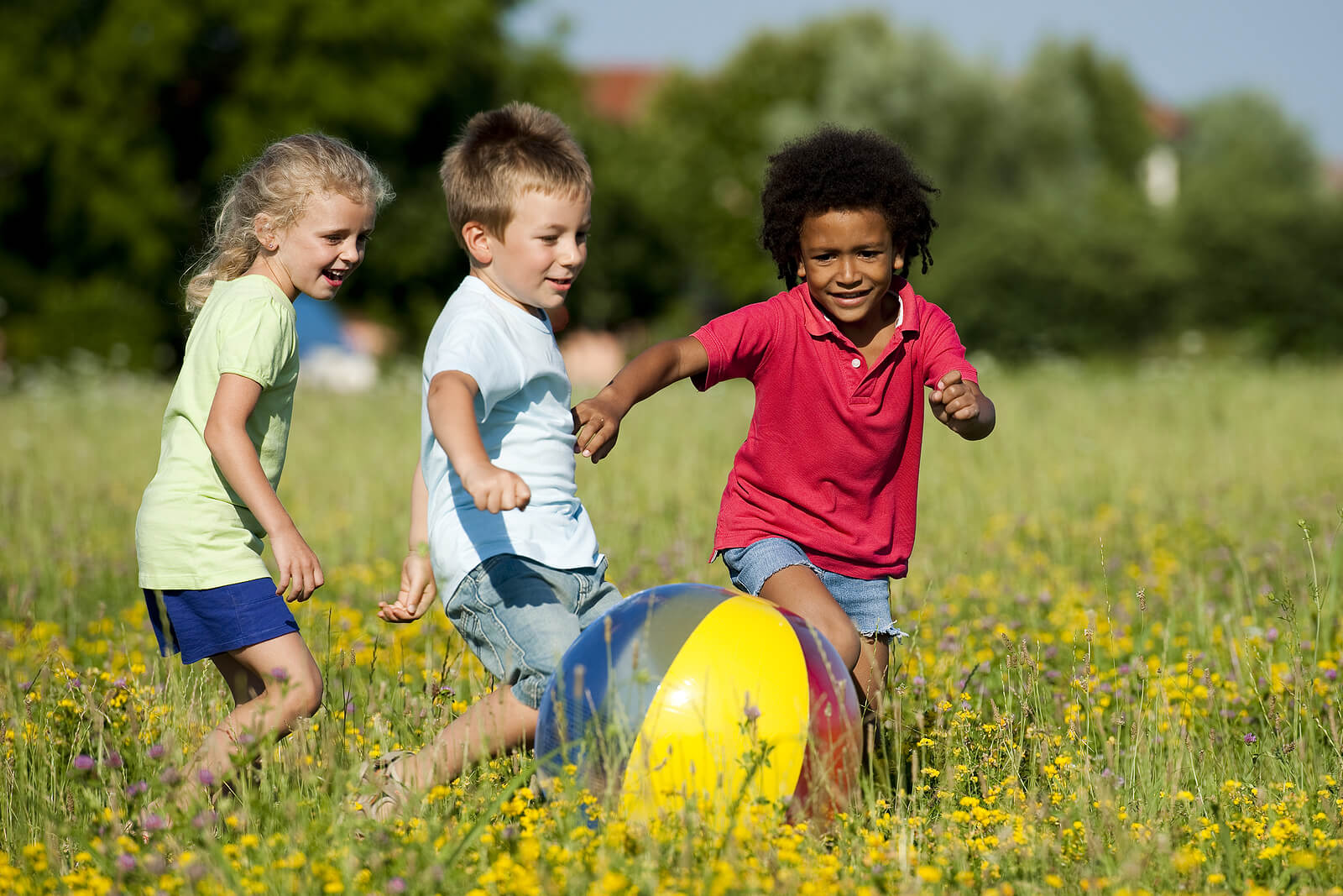 Niños jugando con la pelota al aire libre en verano.