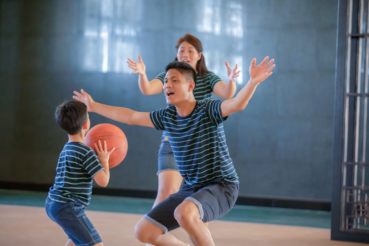 Padres jugando al baloncesto con su hijo para desarrollar sus capacidades.