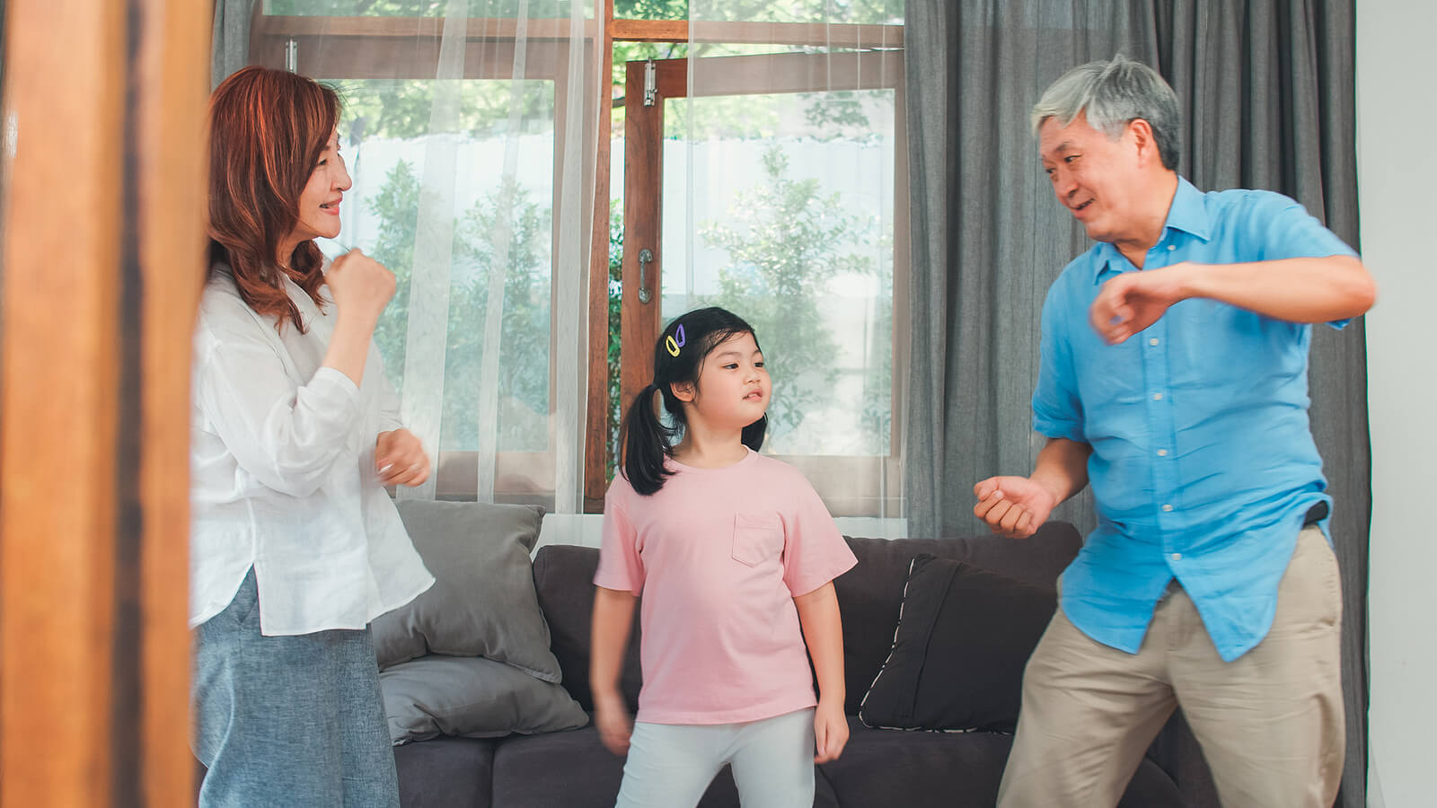 Padres bailando con su hija en el salón de casa para favorecer el desarrollo holístico durante los primero años de su pequeña.