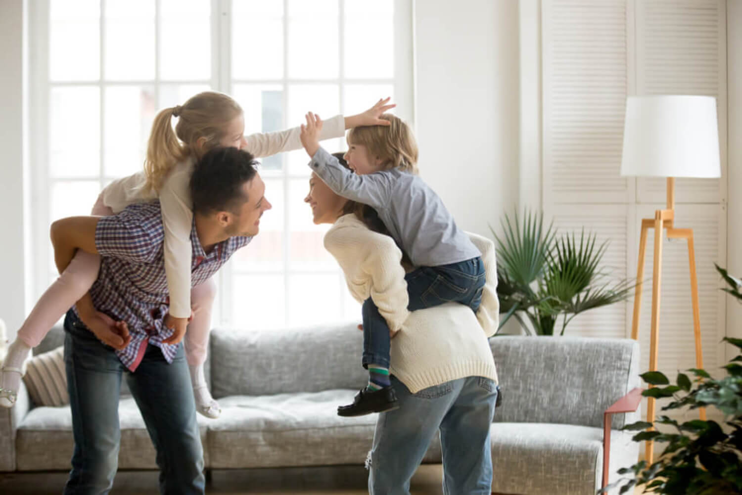 Padres jugando con sus hijos en el salón de casa.