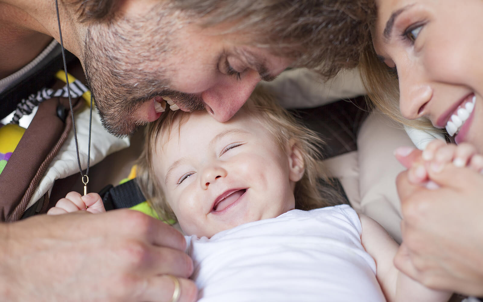 Padres jugando con su bebé y haciéndole reír para promover un apego seguro.
