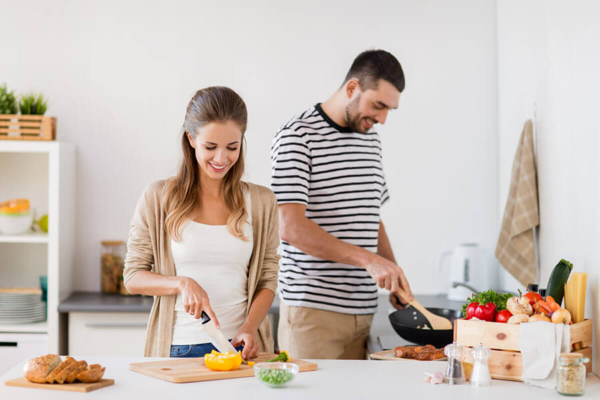 Pareja cocinando de manera saludable debido a la importancia de la vitamina E para la fertilidad.