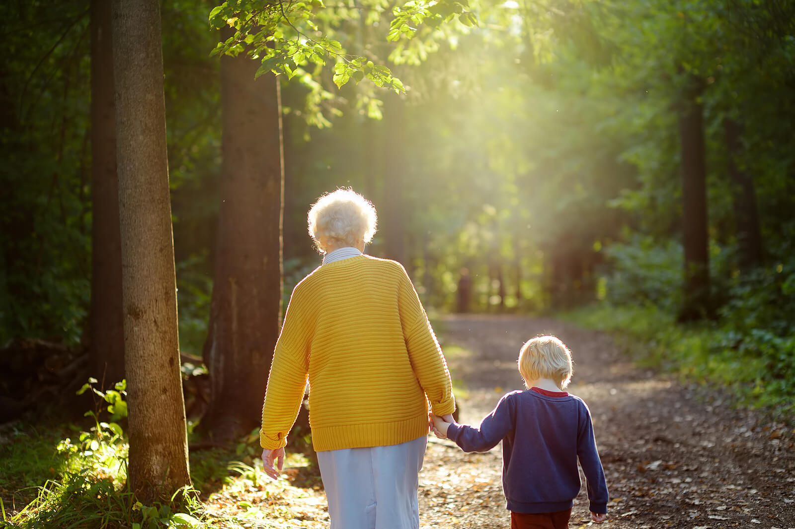 Abuela dando un paseo por el bosque con su nieto.