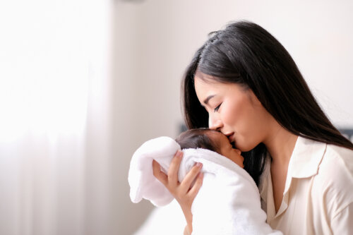 Mamá dando un beso a su bebé recién nacido.