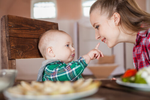 Mamá dando de comer a su bebé en la mesa.