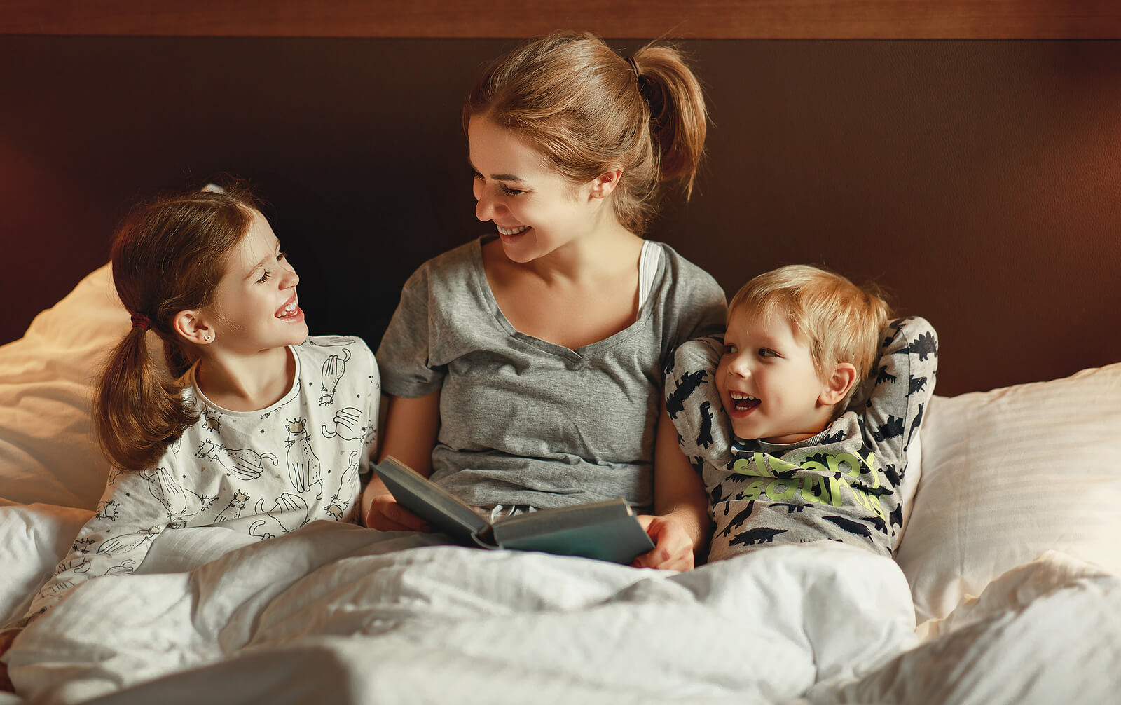 Mãe lendo uma história para seus filhos na cama antes de dormir.