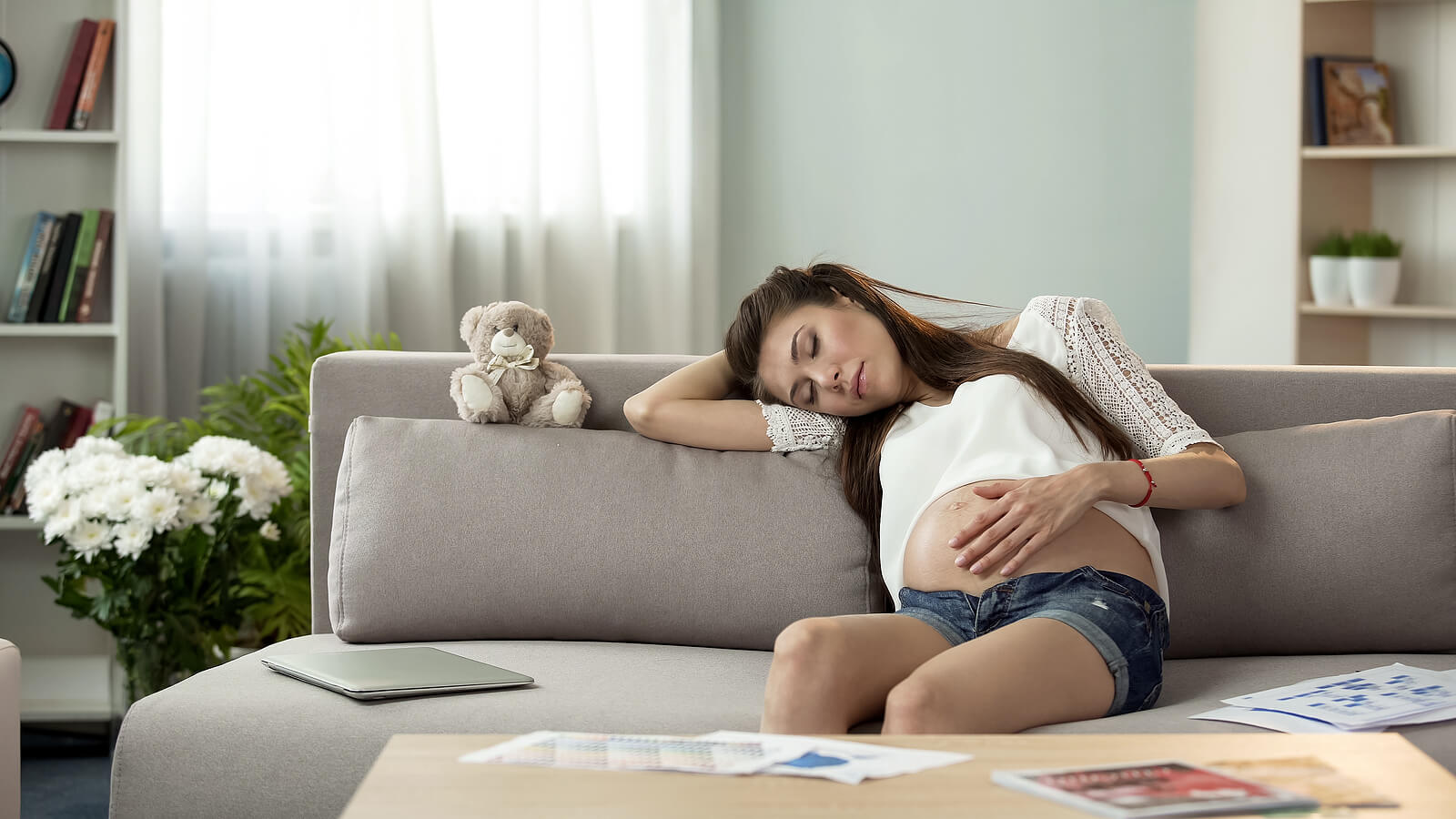Mujer embarazada echándose una siesta en el sofá para mejorar el sueño durante el embarazo.
