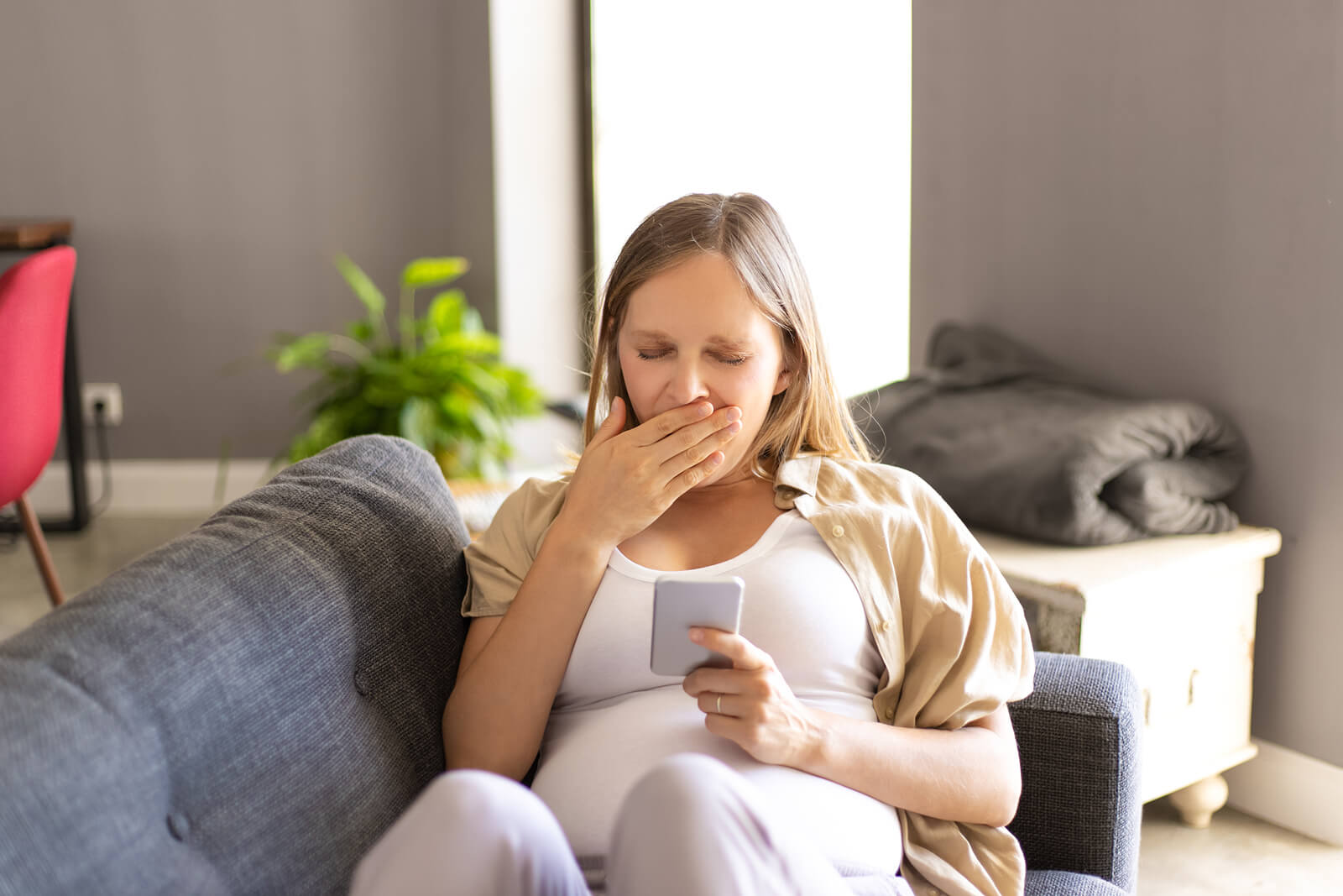 Mujer embarazada sentada en el sofá mirando las 3 cuentas de Instagram que debe seguir.