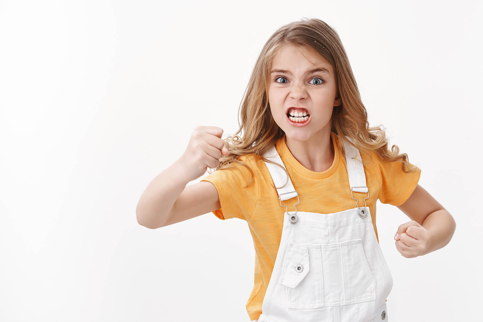 A young girl lifting her fists in the air and clenching her teeth.