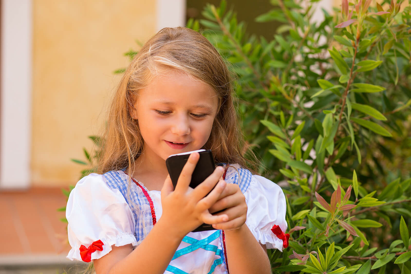 Niña enviando mensaje con el teléfono móvil.