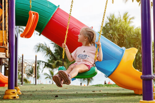 Niña jugando sola en un columpio del parque.