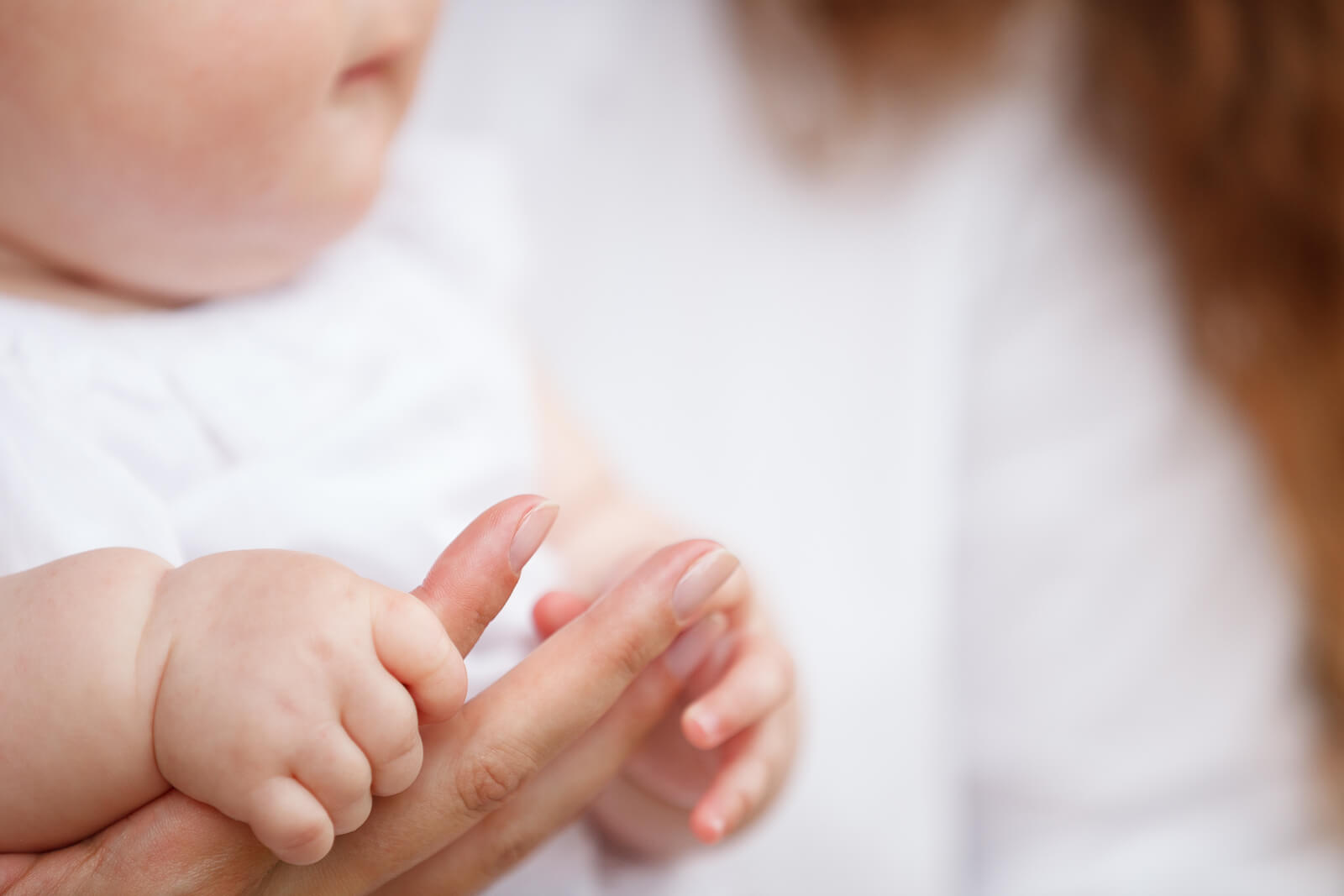 Bebé agarrando el dedo de su madre.
