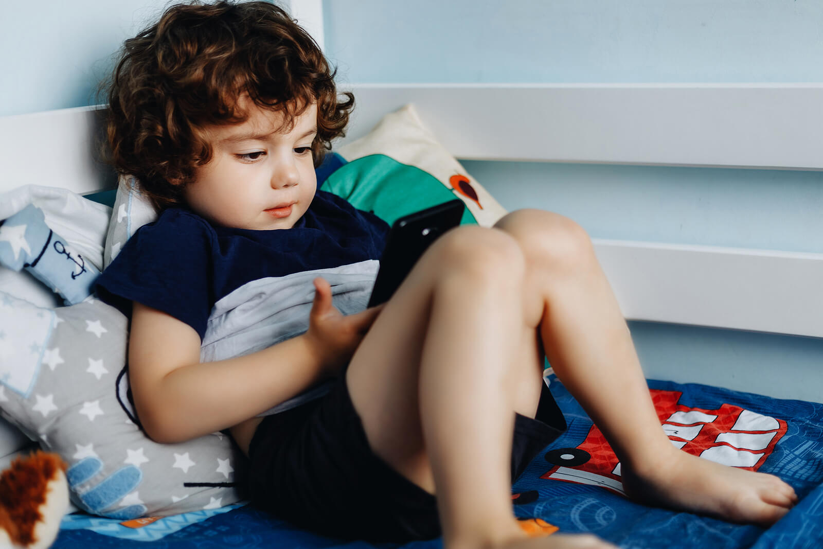 Niño jugando con el móvil porque no es consciente de que el teléfono móvil no es un juguete para niños.