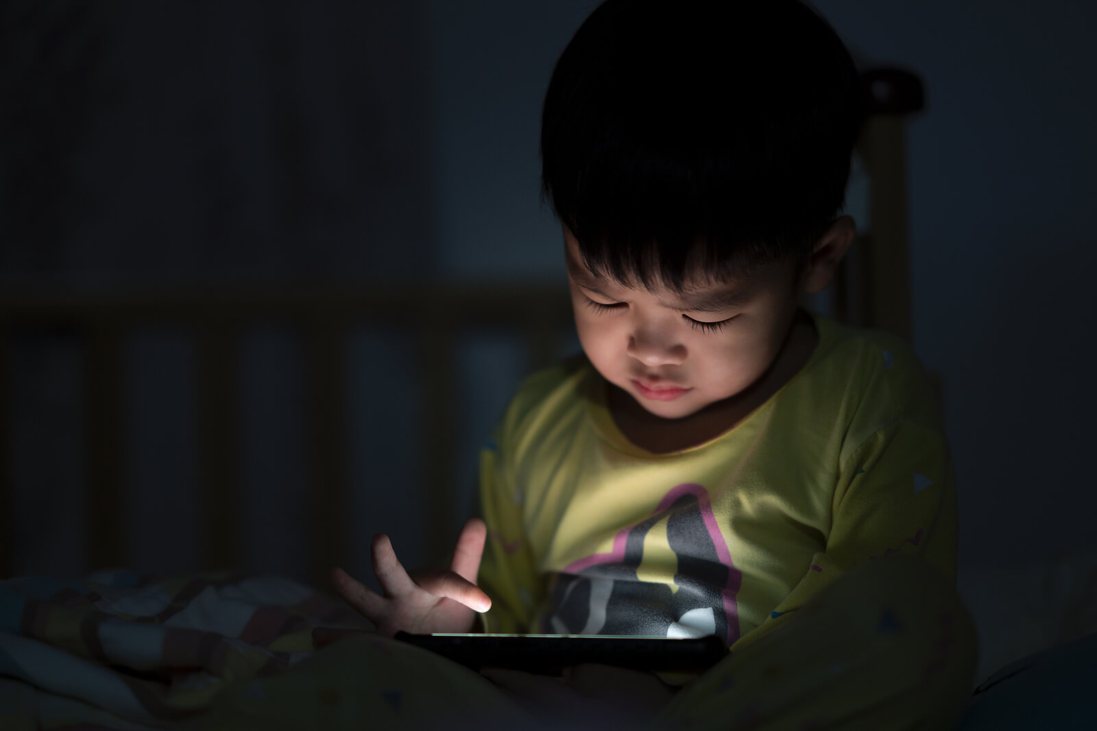 Garçon regardant un film sur une tablette la nuit.