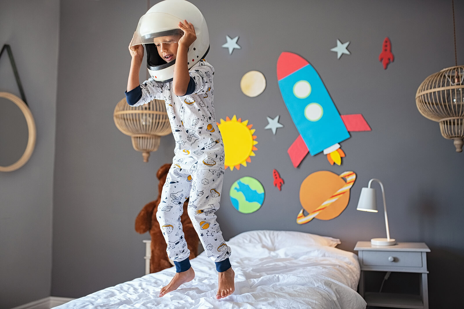 Garçon sautant sur le lit habillé en astronaute.