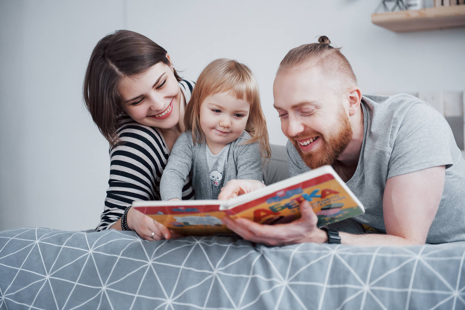 Padres enseñando a leer en voz alta a su hija pequeña.