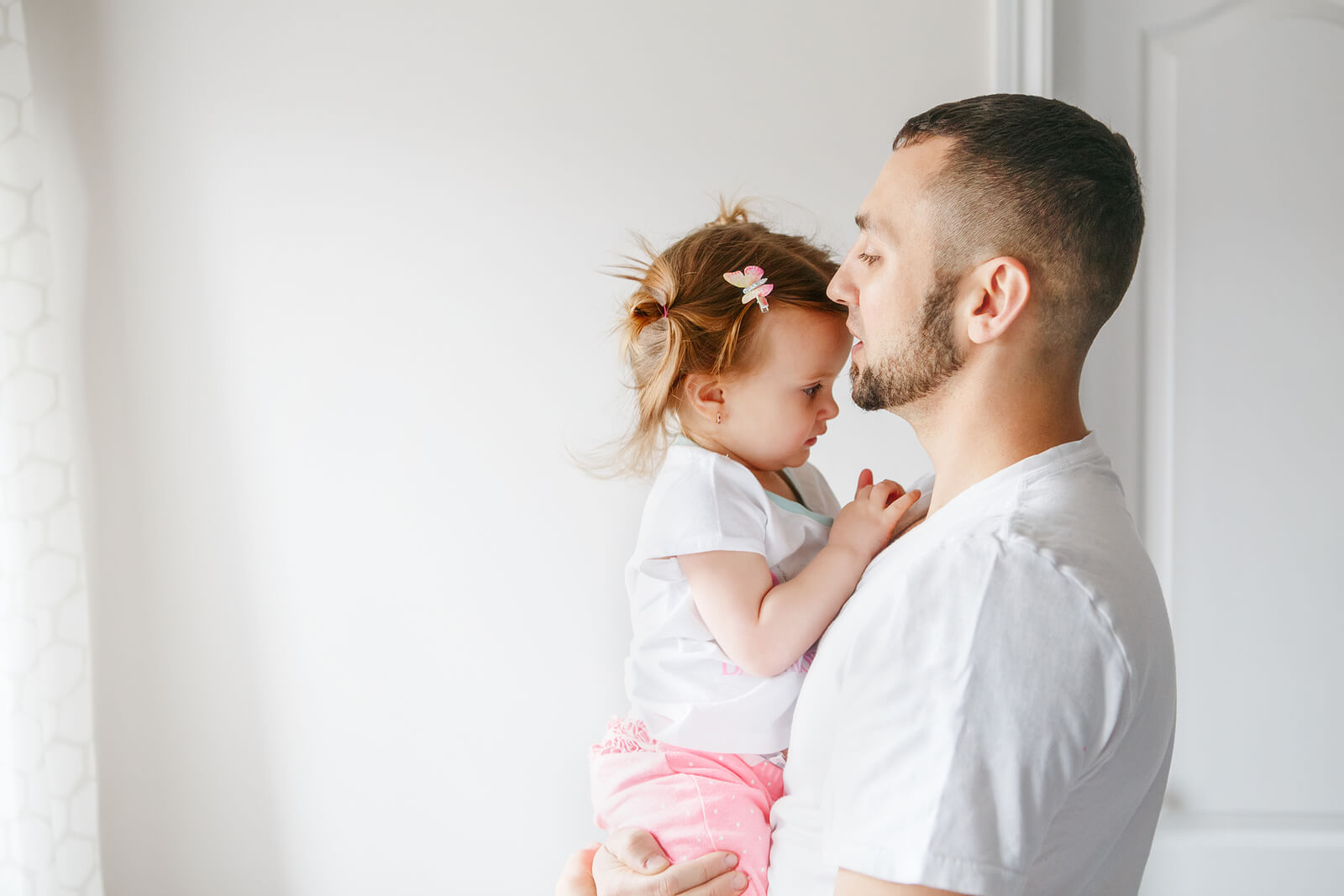 Padre dando un beso a su hija en la frente.