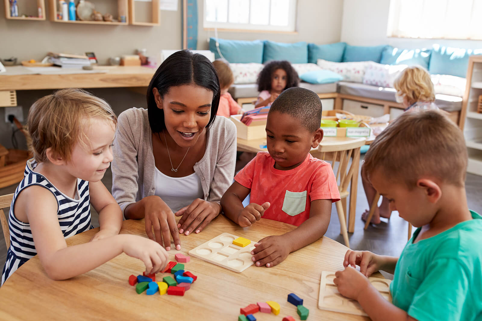 Une enseignante avec ses élèves qui jouent avec un jeu Montessori. 