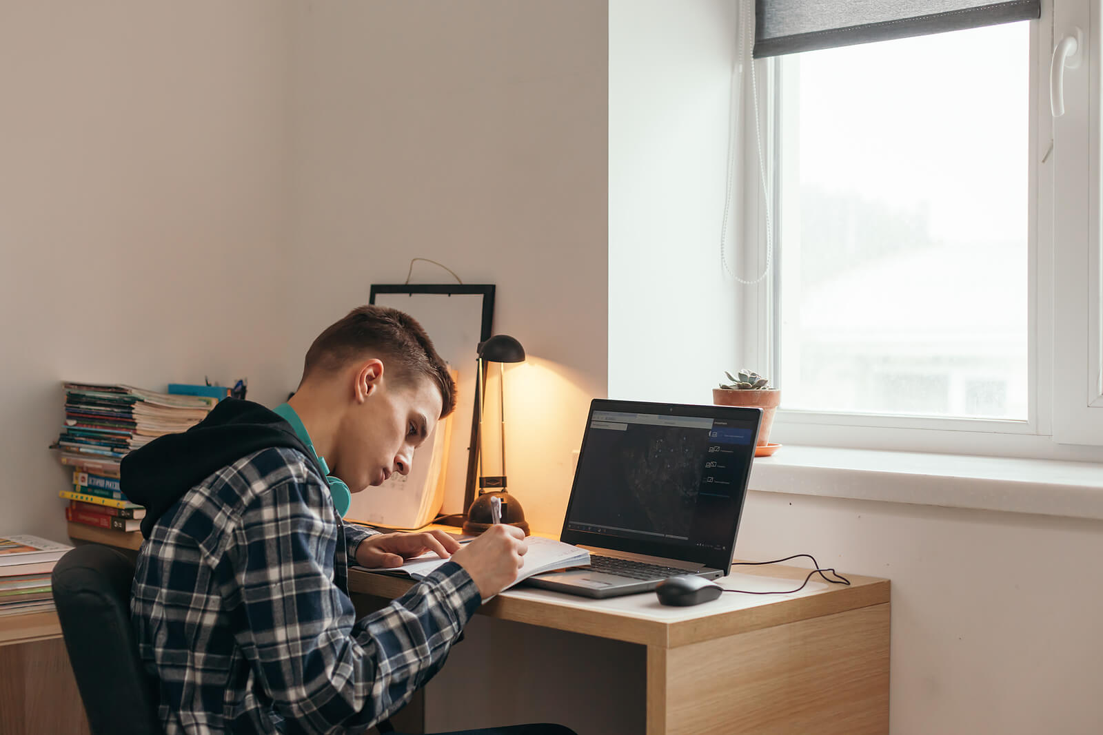 A teen studying at his desk in his room.