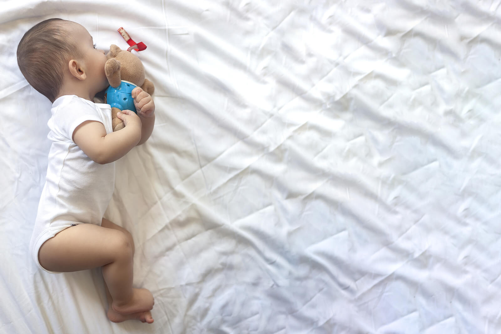 Bebé durmiendo con un peluche para evitar algunos de los errores que cometemos al acostar al niño.