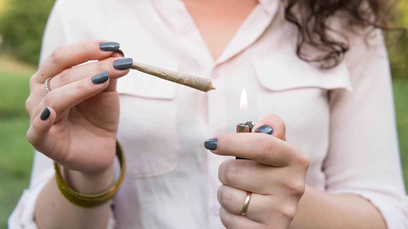 Chica adolescente encendiéndose un porro de cannabis.