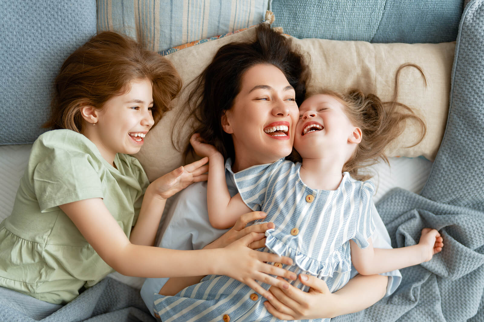 Madre disfrutando con sus hijas mientras se ríen en la diferentes etapas del humor infantil.