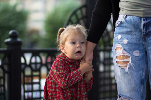 Niña pequeña asustada agarrada de la mano de su madre.