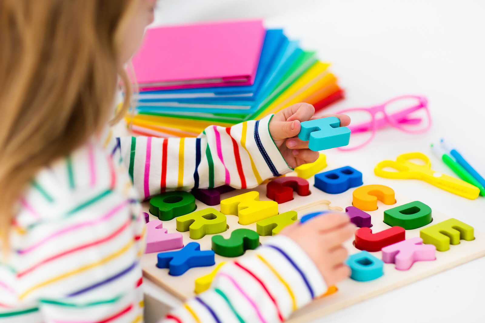 Niña haciendo rompecabezas con letras.