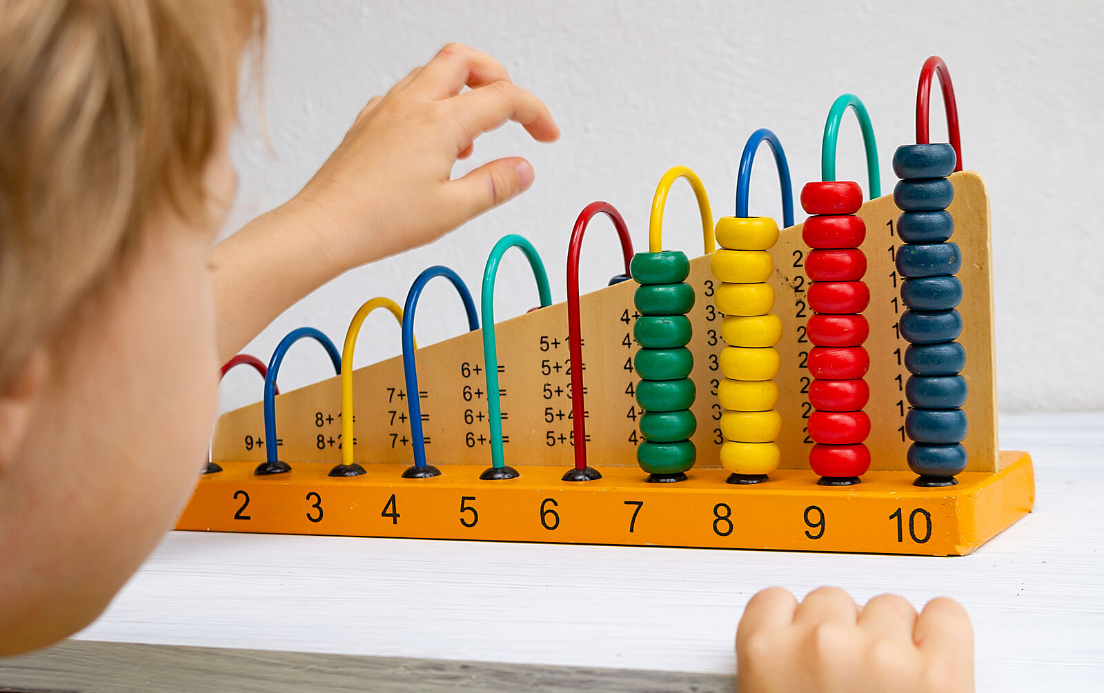 Niño aprendiendo matemáticas tempranas con un ábaco gracias al método Montessori.