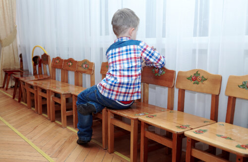 Niño con autismo y síndrome de savant sentado en una silla de espaldas.