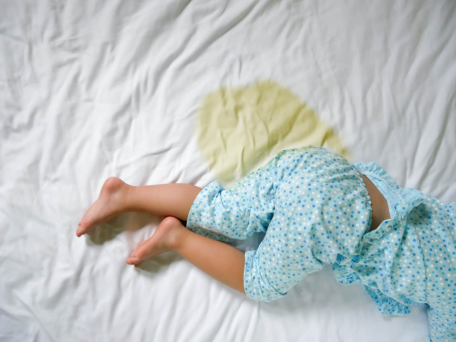 Niño con las sábanas mojadas porque se ha hecho pis en la cama por la noche.