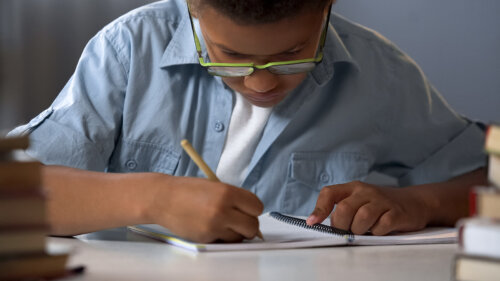 Niño con dislexia escribiendo en un cuaderno.