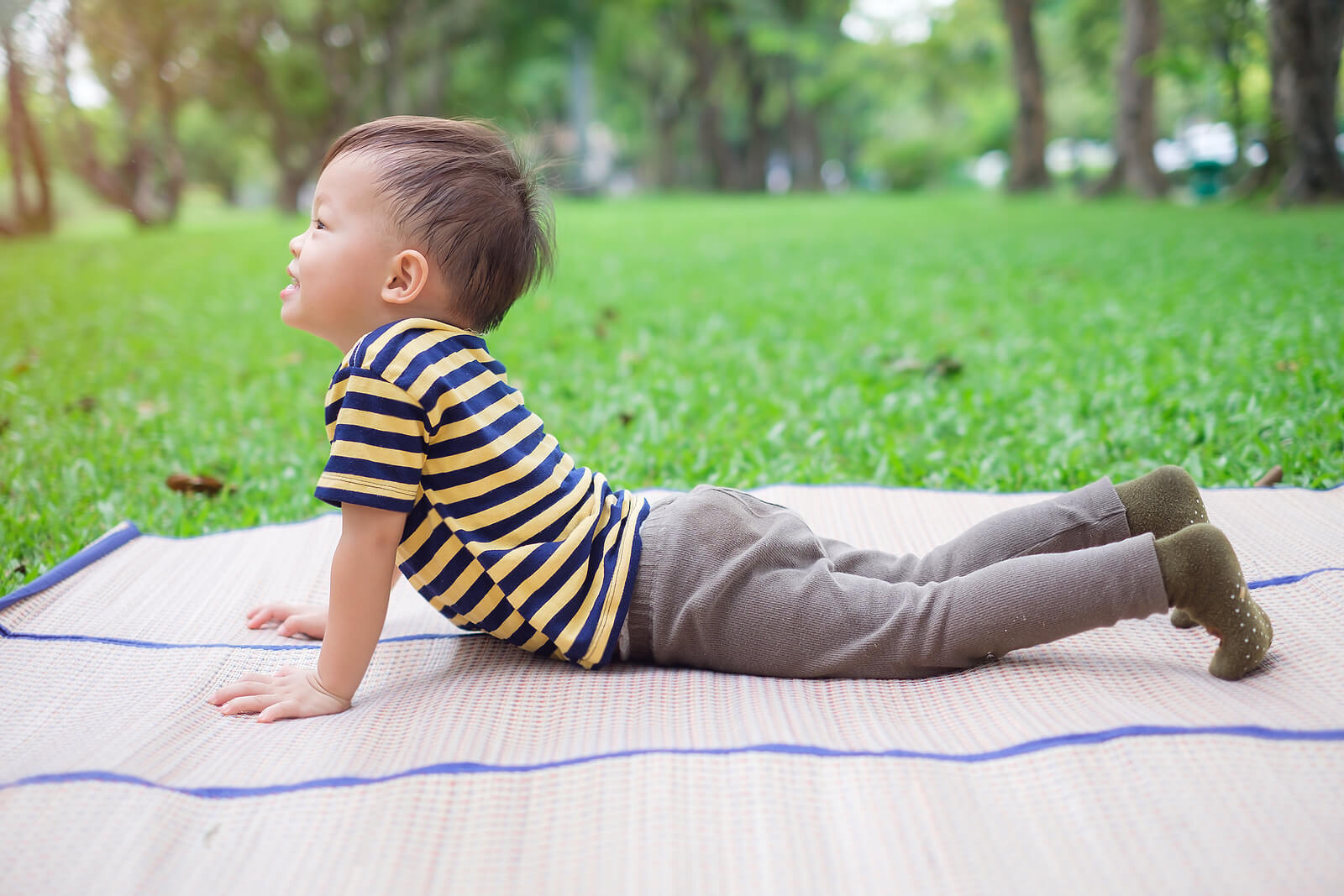 Enfant allongé sur le sol faisant la posture du chien tourné vers le haut.
