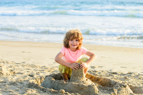 Niño jugando con la arena en la playa.