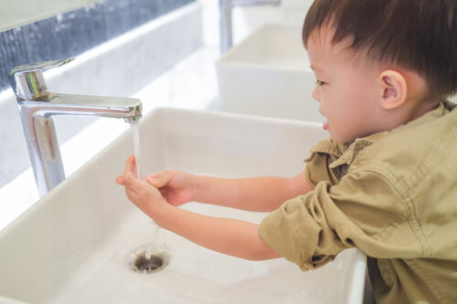 Niño lavándose las manos solo en el baño.