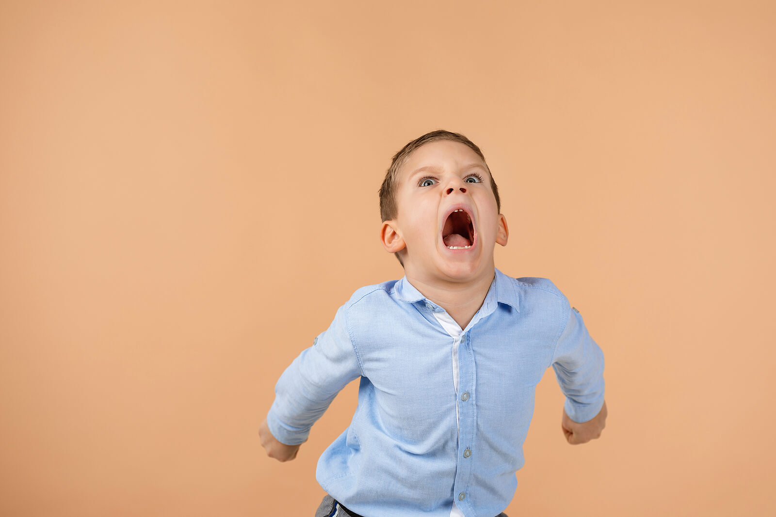 Niño gritando lleno de ira en público.