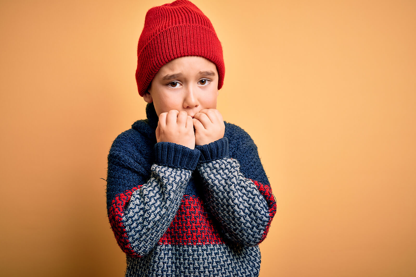 En skremt gutt biter negler.